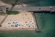 Aerial view of State Beach each and bridge with jumpers splashing into the water