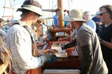 Oyster farmers shuck shellfish aboard a boat.